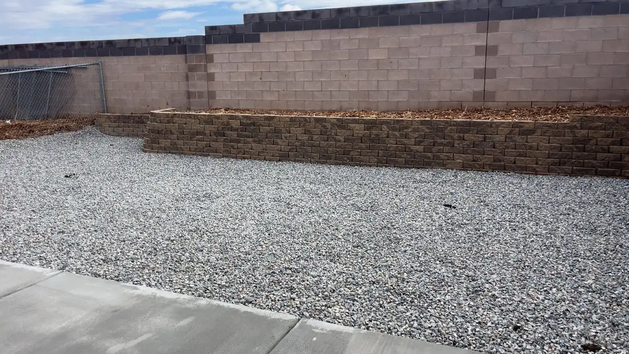Stacked block planter wall along a back wall with gravel in front