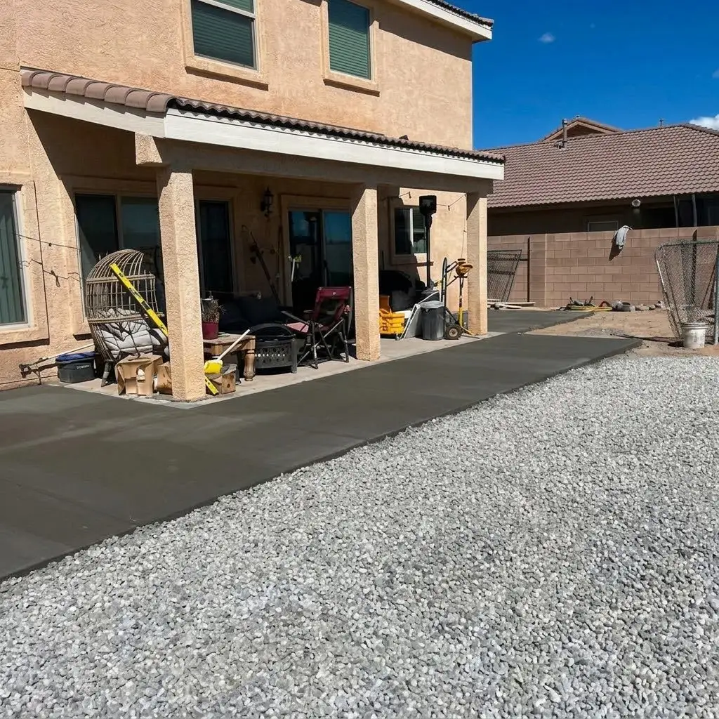 New concrete pad along the patio with gravel across the yard